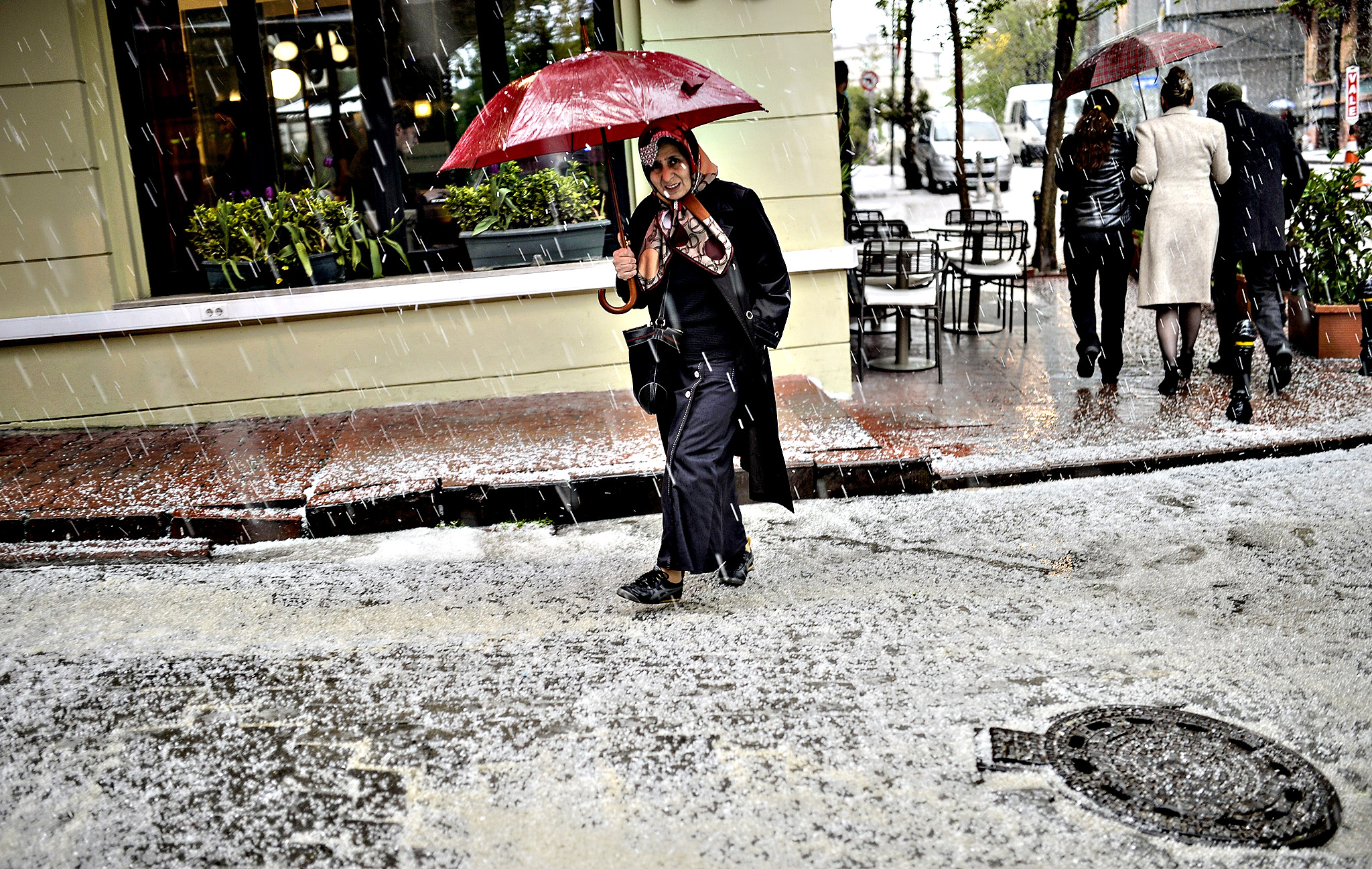 A woman walks under an umbrella during a sudden hail-storm on Wednesday, in Istanbul