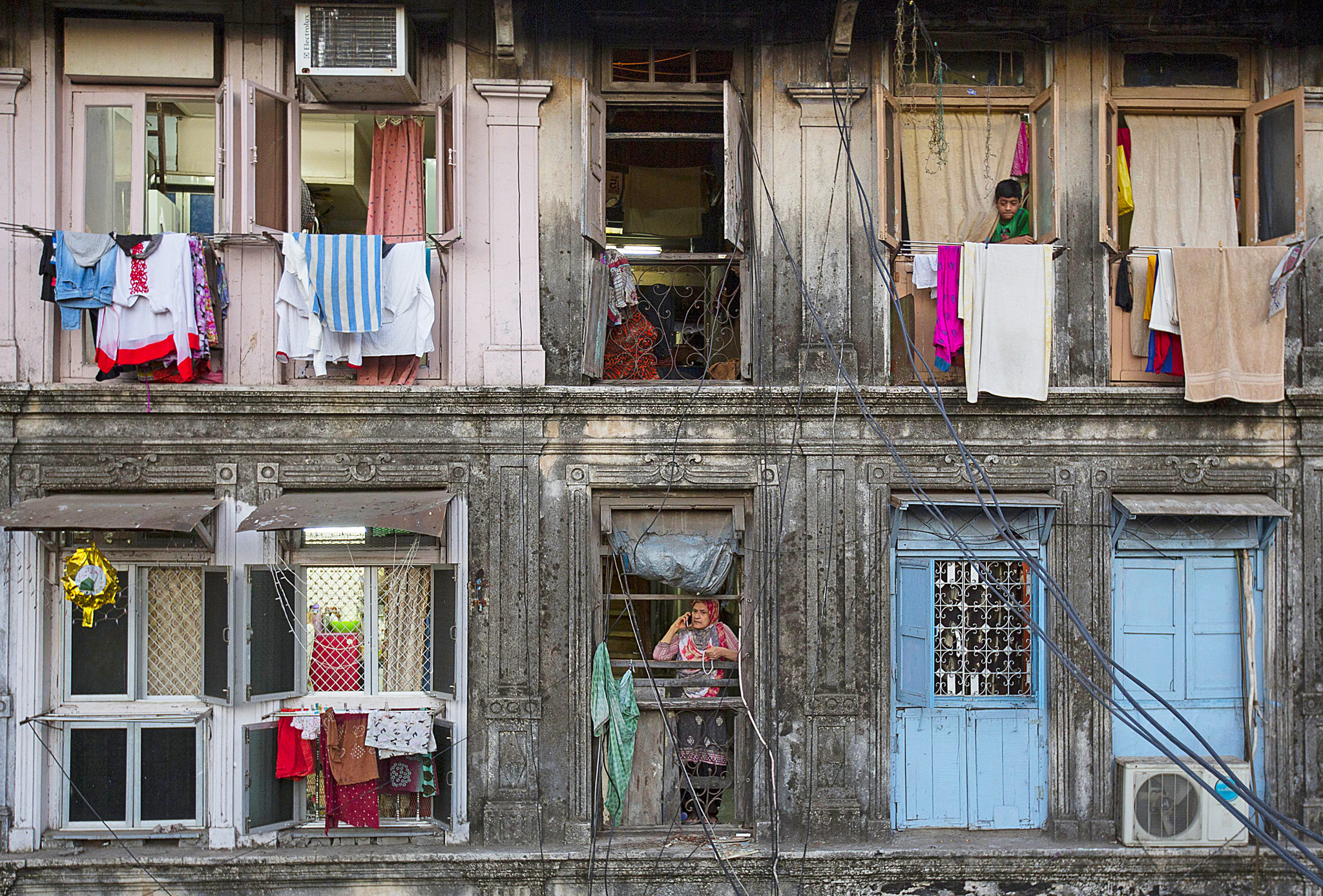 Wider Image: Renting in Mumbai Per Square Foot...Residents look out of windows of an apartment in Mumbai March 15, 2015. The cost for buying a 200 square feet (18 square meters) one-bedroom apartment in this building is around 25,000 Indian rupees per square feet ($ 400) or 5,000,000 Indian rupees ($ 80,000). The rent for an apartment in the same building is around 12,000 Indian rupees ($ 190) per month. REUTERS/Danish Siddiqui  TPX IMAGES OF THE DAY PICTURE 05 OF 22 FOR WIDER IMAGE STORY "RENTING IN MUMBAI PER SQUARE FOOT" SEARCH "RENTING SIDDIQUI" FOR ALL IMAGES